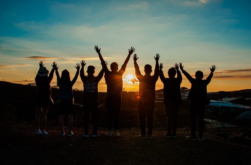 Silhouette picture of a group of young people raising their hands